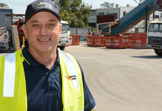 Michael in a vest stands in front of Speedy Bin office Brisbane
